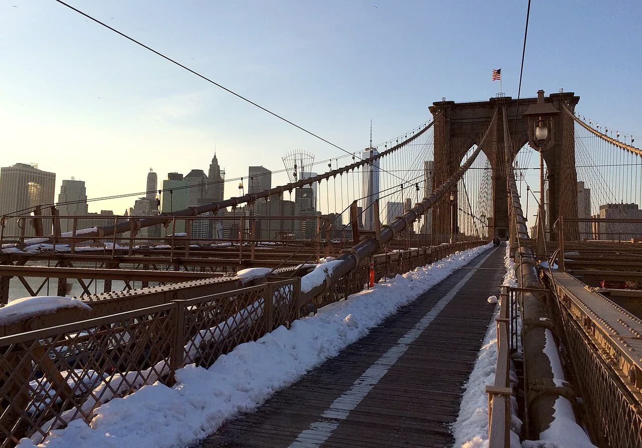 Brooklyn Bridge walkway and stone tower with the Manhattan skyline beyond