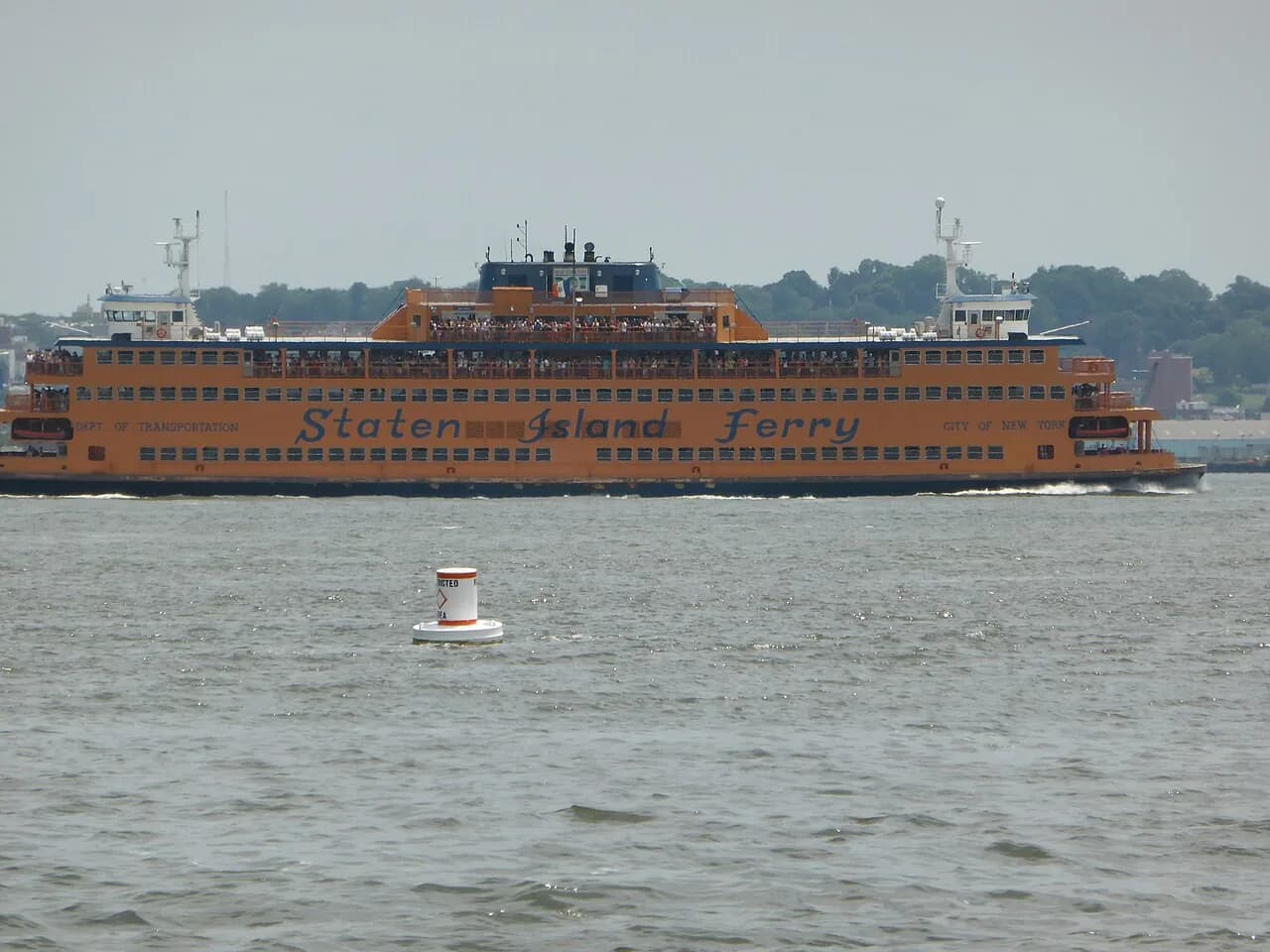 An orange Staten Island Ferry crossing New York Harbor