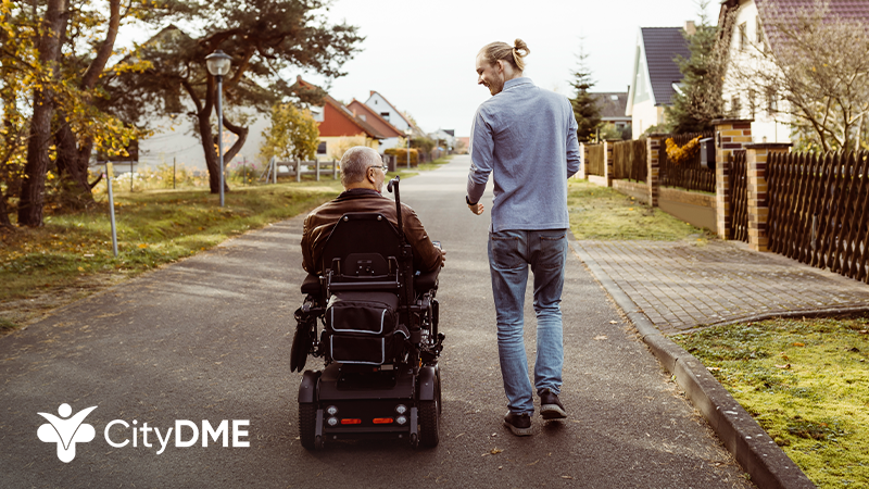 Man walking next to another man in a wheelchair outdoors