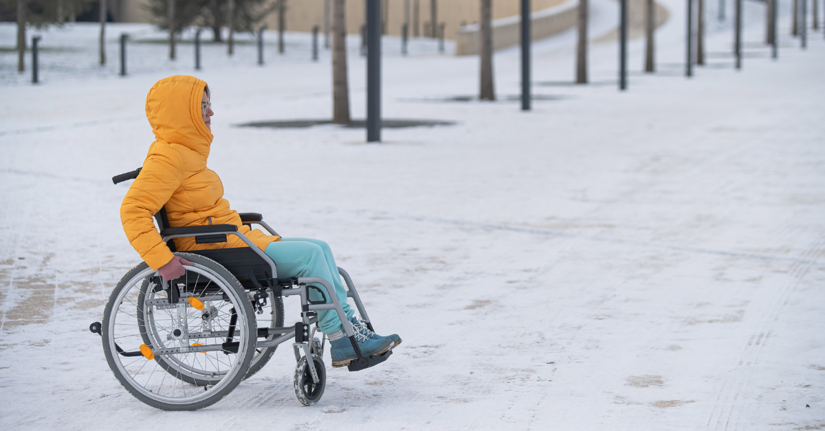 Woman dressed for winter in wheelchair riding out in the snow