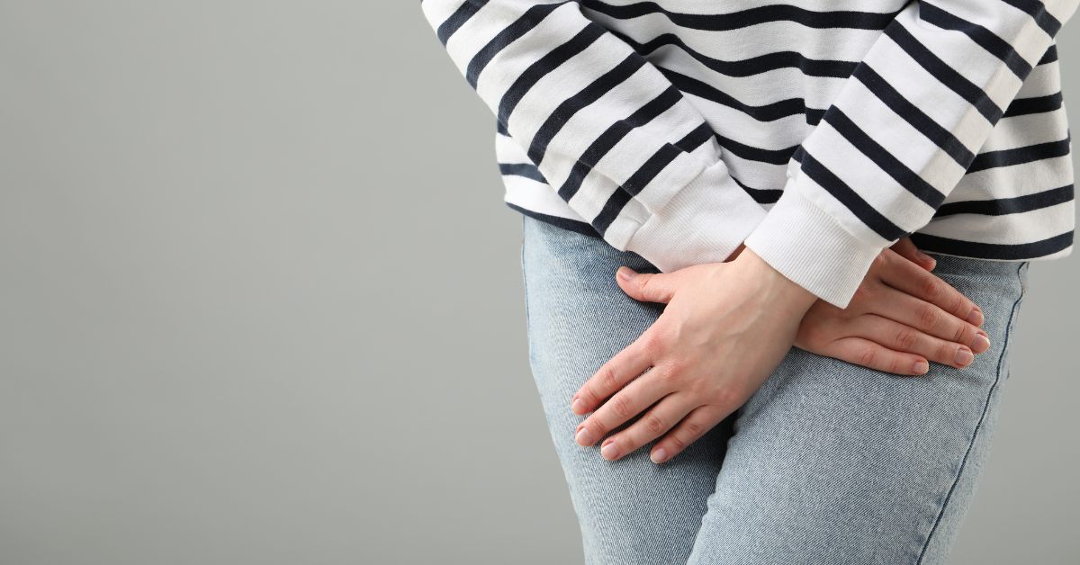 Person's hands in front of her bladder region to signal urge to use restroom
