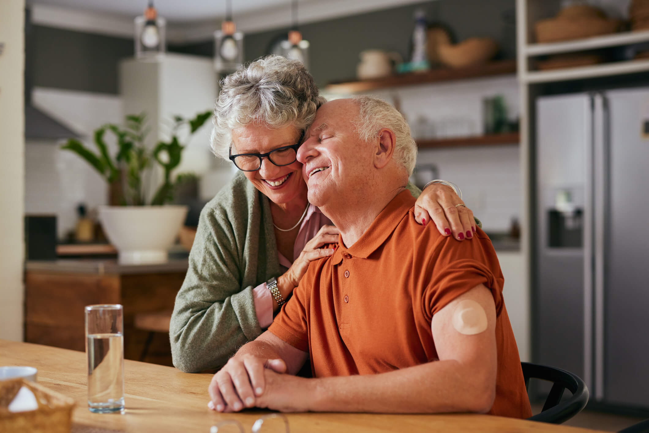 Happy older couple embracing with man wearing a CGM sensor on his arm