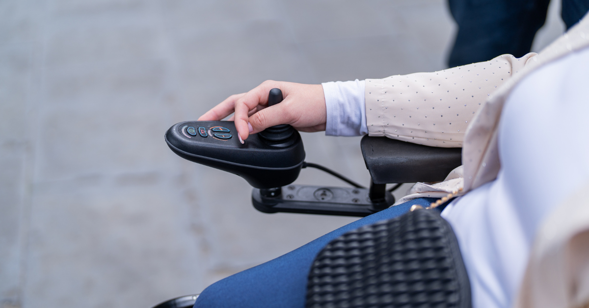 Woman sitting in power wheelchair with hand on joystick