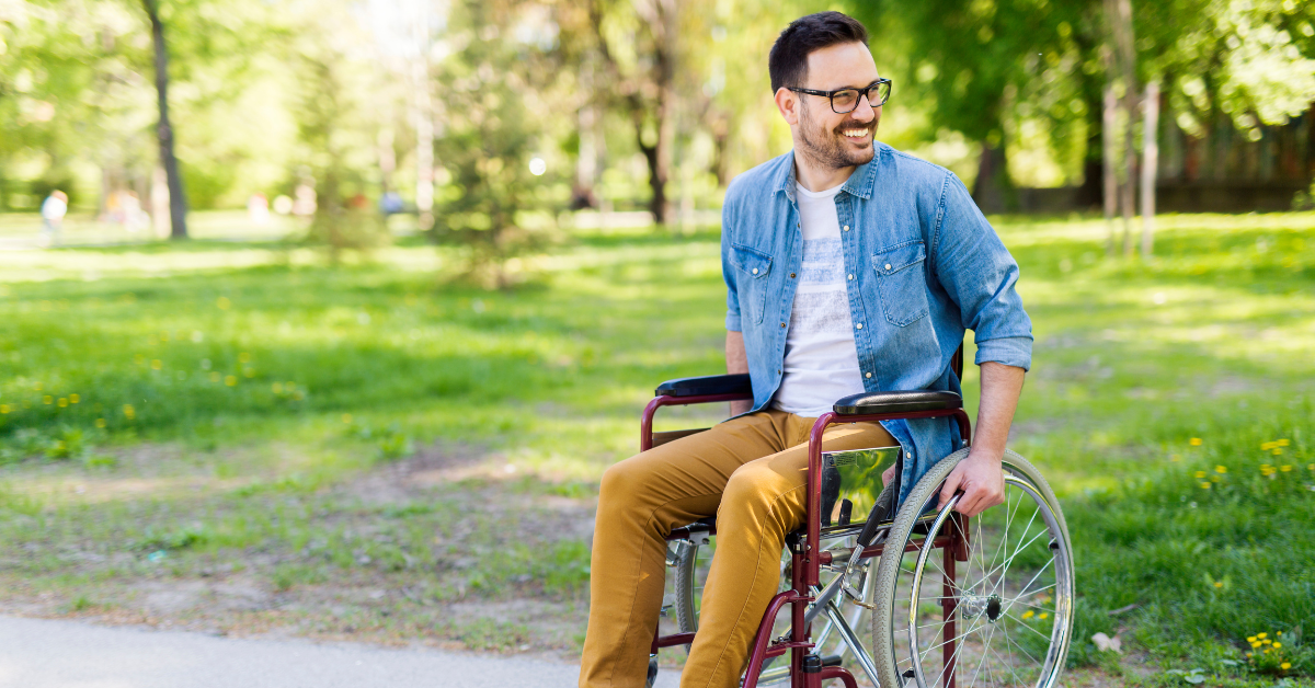 Man sitting in wheelchair outside int he sunshine smiling