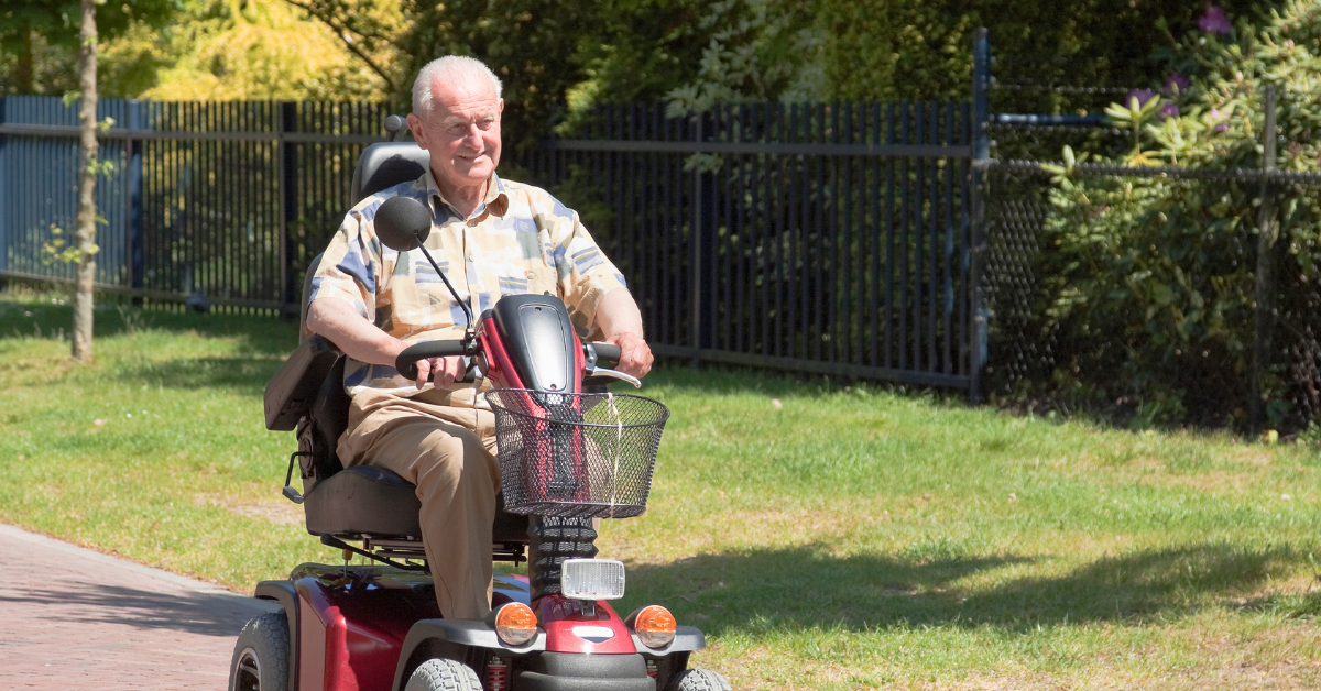 Senior man smiling while riding a mobility scooter outside in sunny weather