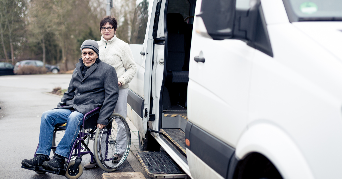 Man in wheelchair being pushed by wife to car ramp