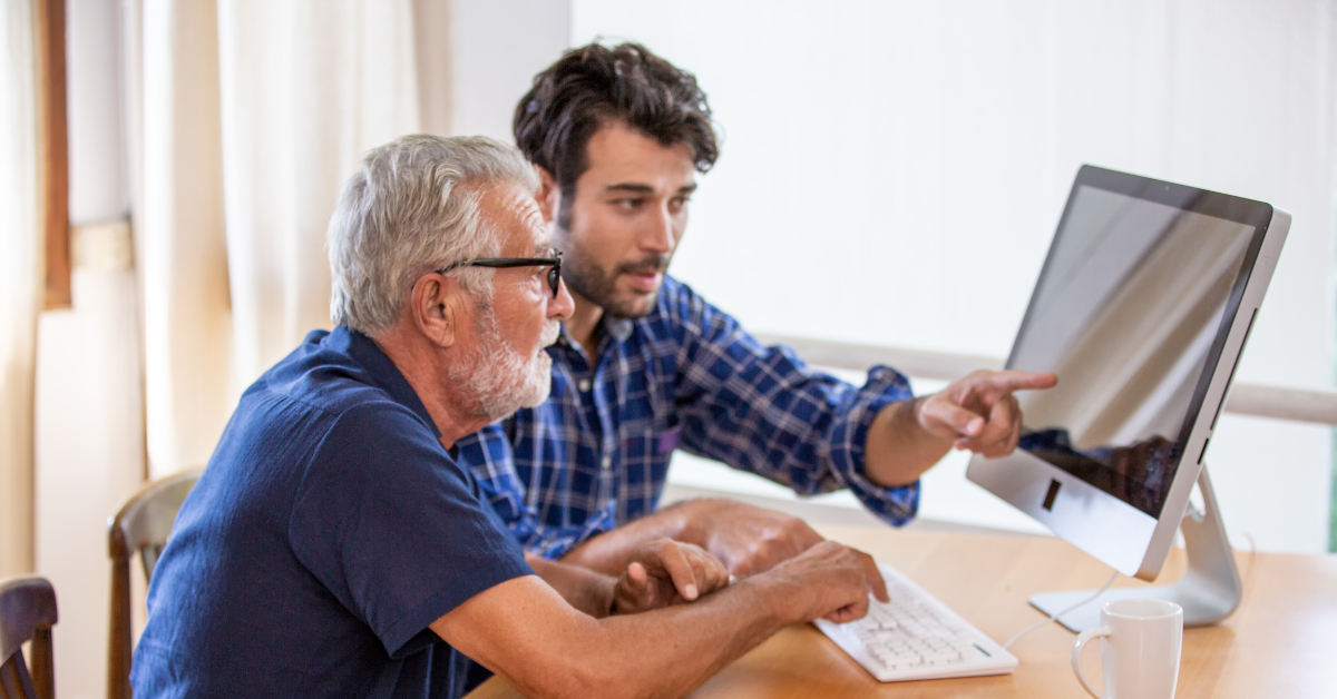 Adult man helping elderly father order medical supplies on desktop computer