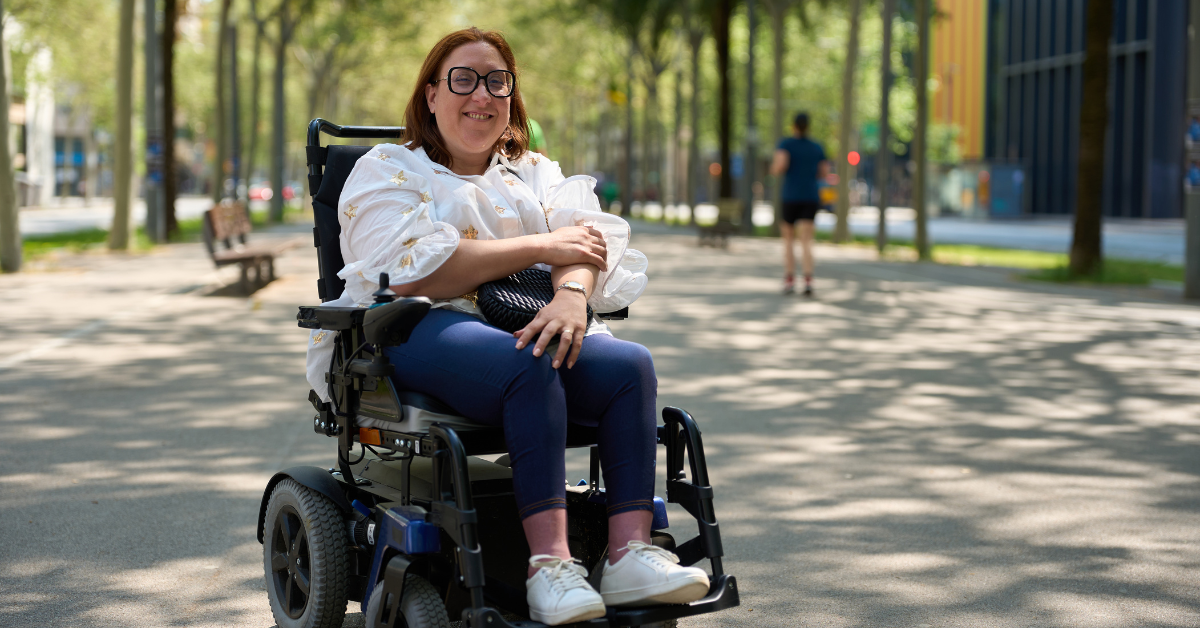 Woman smiling while sitting in power chair on sidewalk