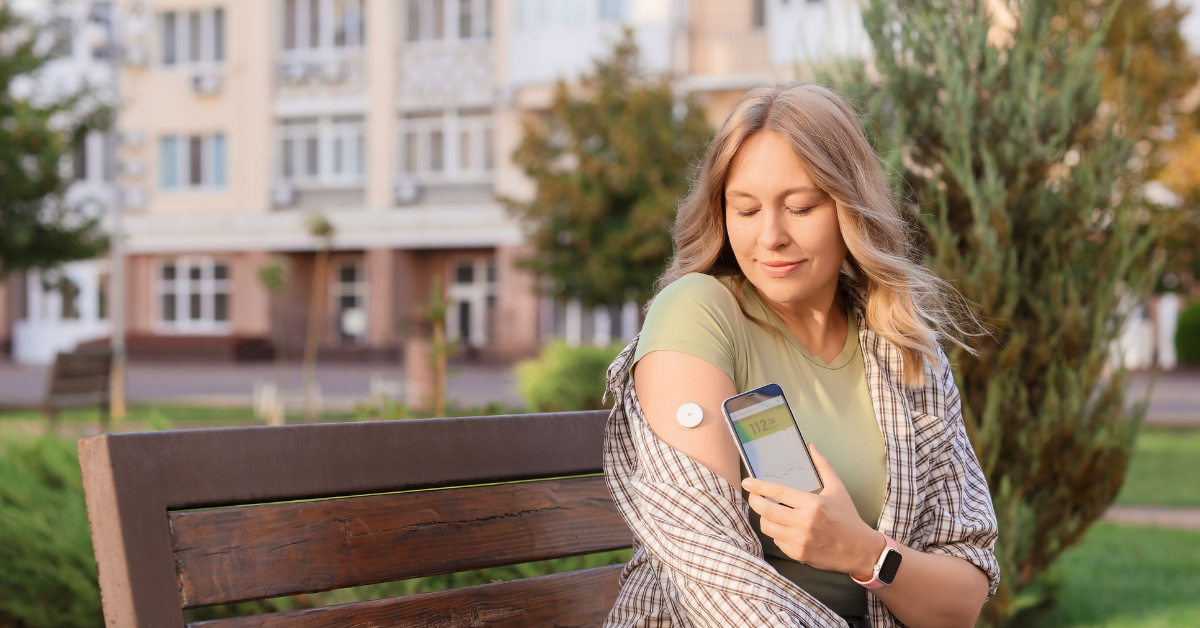 Woman checking her glucose level with her phone on her continuous glucose monitor